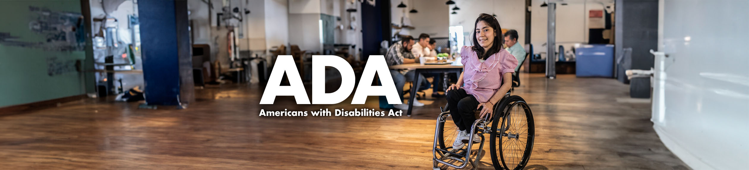 Americans with Disabilities Act (ADA) - A young woman with a disability in a wheel chair at her company office meeting.